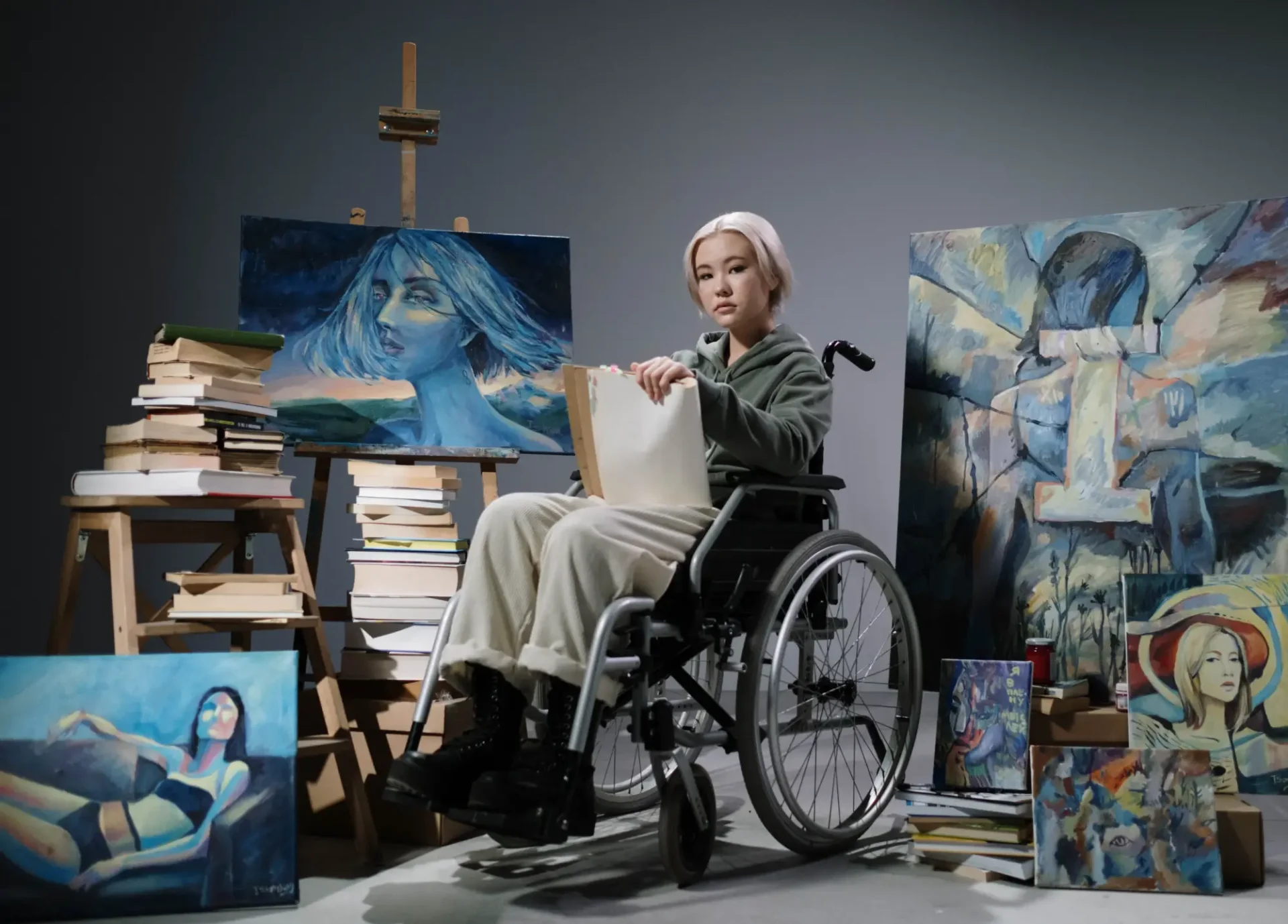 A woman in a wheelchair painting at an art studio.