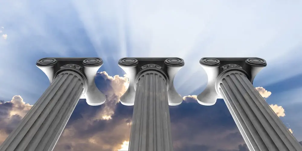 A group of pillars with the sun shining through them.